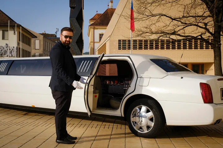 Taxi Leo Chauffeur öffnet die Tür der Cadillac Stretchlimousine